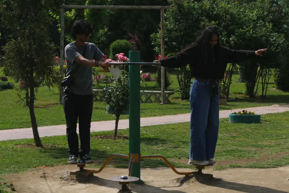 Two people balancing on outdoor exercise equipment in a park